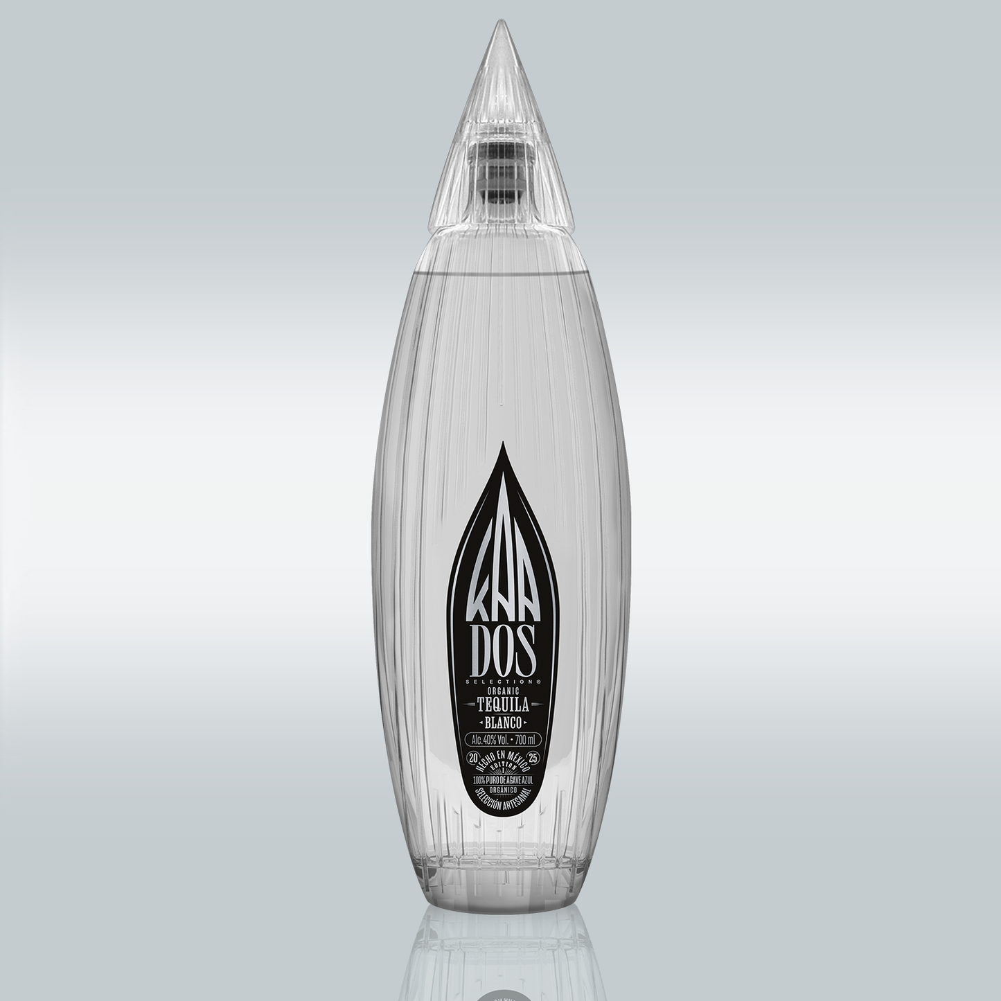 KA DOS Blanco bottle in sleek clear glass with vertical grooves and a sharp, faceted agave-leaf-shaped cap. Black-and-white front label features the KA DOS logo, “Organic Tequila Blanco”, 40% vol., 700 ml, and “100% Puro de Agave Azul”. Clean and modern design with artisanal detailing.