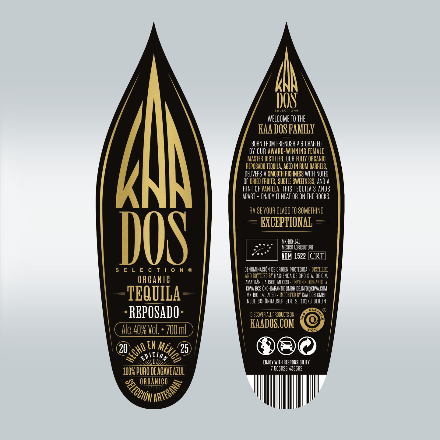Close-up of KA DOS Reposado bottle labels, shaped like stylized agave leaves. Front label in gold on black reads: “Organic Tequila Reposado”, 40% vol., 700 ml, and “100% Puro de Agave Azul”. Back label highlights aging in rum barrels, tasting notes of dried fruits and vanilla, and brand story centered on a female master distiller. Includes CRT and NOM 1522 certifications, website, and barcode.
