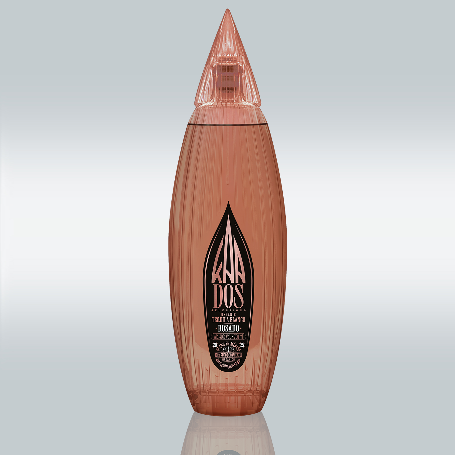 Studio shot of the KA DOS Rosado bottle centered on a gradient white-to-grey background. The sleek, vertically ribbed glass bottle in a warm rosé tone is shaped like an abstract agave leaf with a pointed, faceted cap. A large black KA DOS logo is prominently displayed on the front label, with details in gold and white text about the tequila’s organic origin, volume (700 ml), and alcohol content (40% vol).